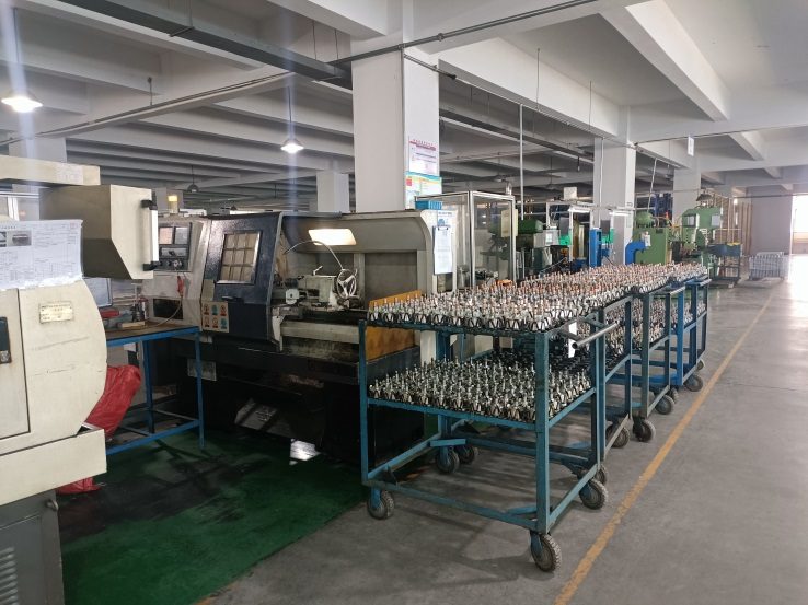 CNC lathe with rows of starter-motor armatures on rolling carts, PICO Changshu